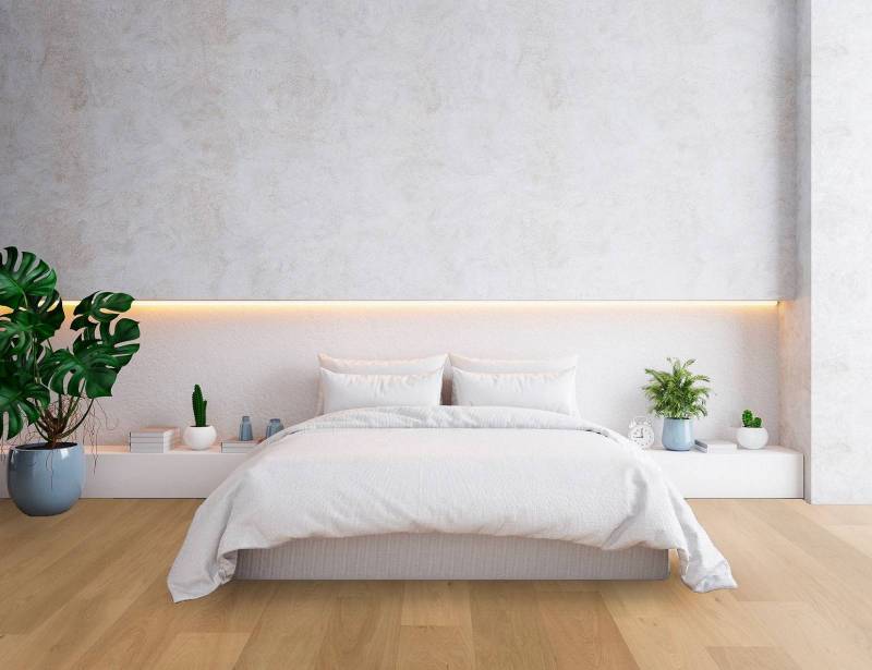 Chambre moderne épurée, lit blanc, éclairage ambiance, plantes vertes, murs texturés clairs, parquet bois.