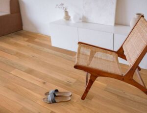 Intérieur moderne avec parquet en bois clair. Chaise pliante en rotin et sandales rayées sur le sol.
