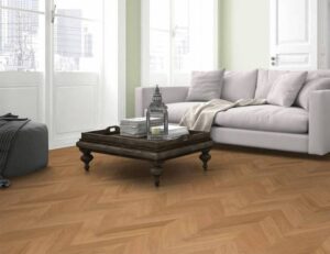 Salon moderne avec canapé blanc et parquet en bois clair posé en chevron, créant une ambiance lumineuse.