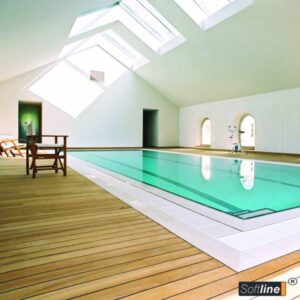 Grande piscine intérieure Softline baignée de lumière naturelle par des puits de lumière et un sol en bois. Un vélo d'exercice est visible.