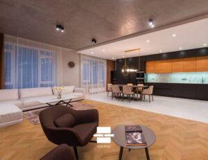 Salon, salle à manger et cuisine ouverts avec parquet chevrons SOBOPLAC. Canapé blanc, fauteuil marron. Cuisine moderne.