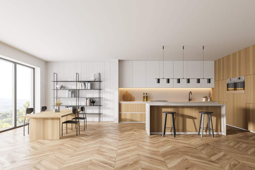 Cuisine moderne ouverte bois clair et blanc | Design intérieur Cuisine moderne ouverte bois clair et blanc, îlot central, salle à manger avec table en bois et chaises noires. Parquet chevrons, vue nature.