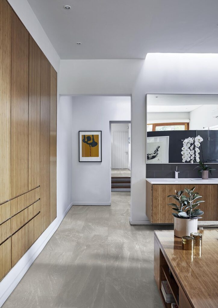 Couloir lumineux au design minimaliste : carrelage gris effet marbre, armoires en bambou, et œuvre d'art jaune audacieuse.