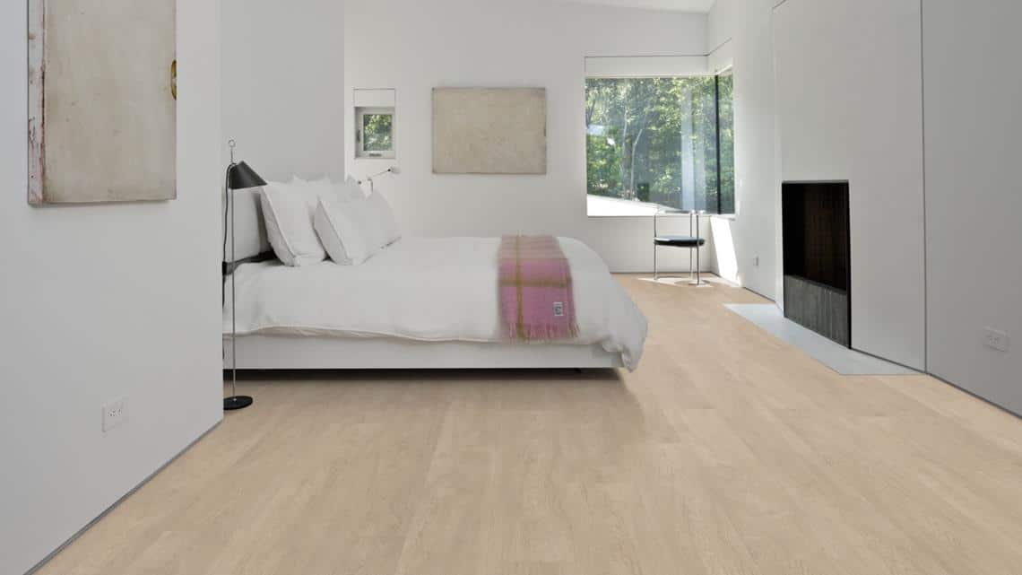 Chambre minimaliste moderne avec plancher en bois clair, lit blanc douillet, cheminée intégrée et vue panoramique sur la nature.